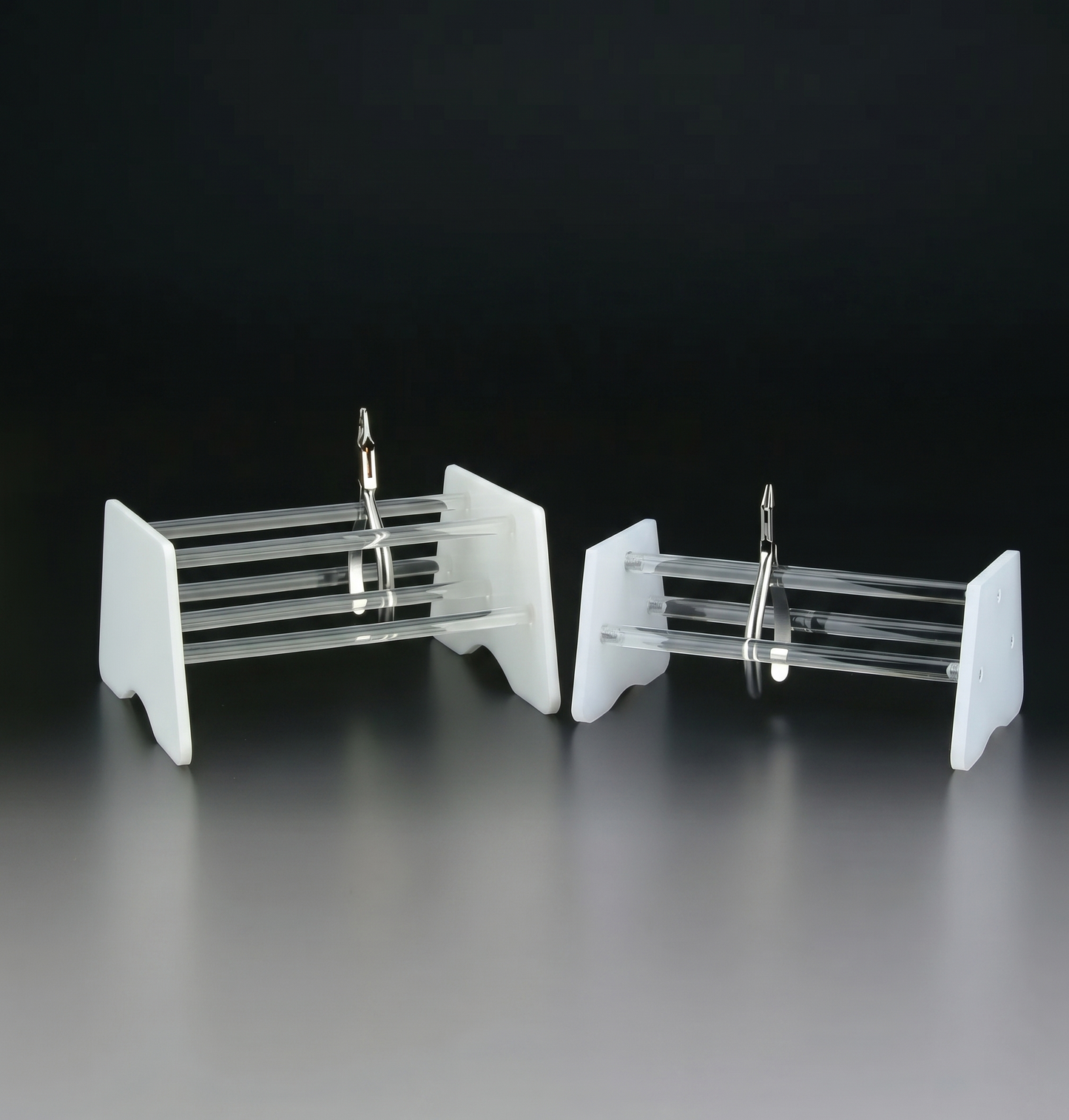 Clear plastic earring display stand on a reflective surface with a dark background
