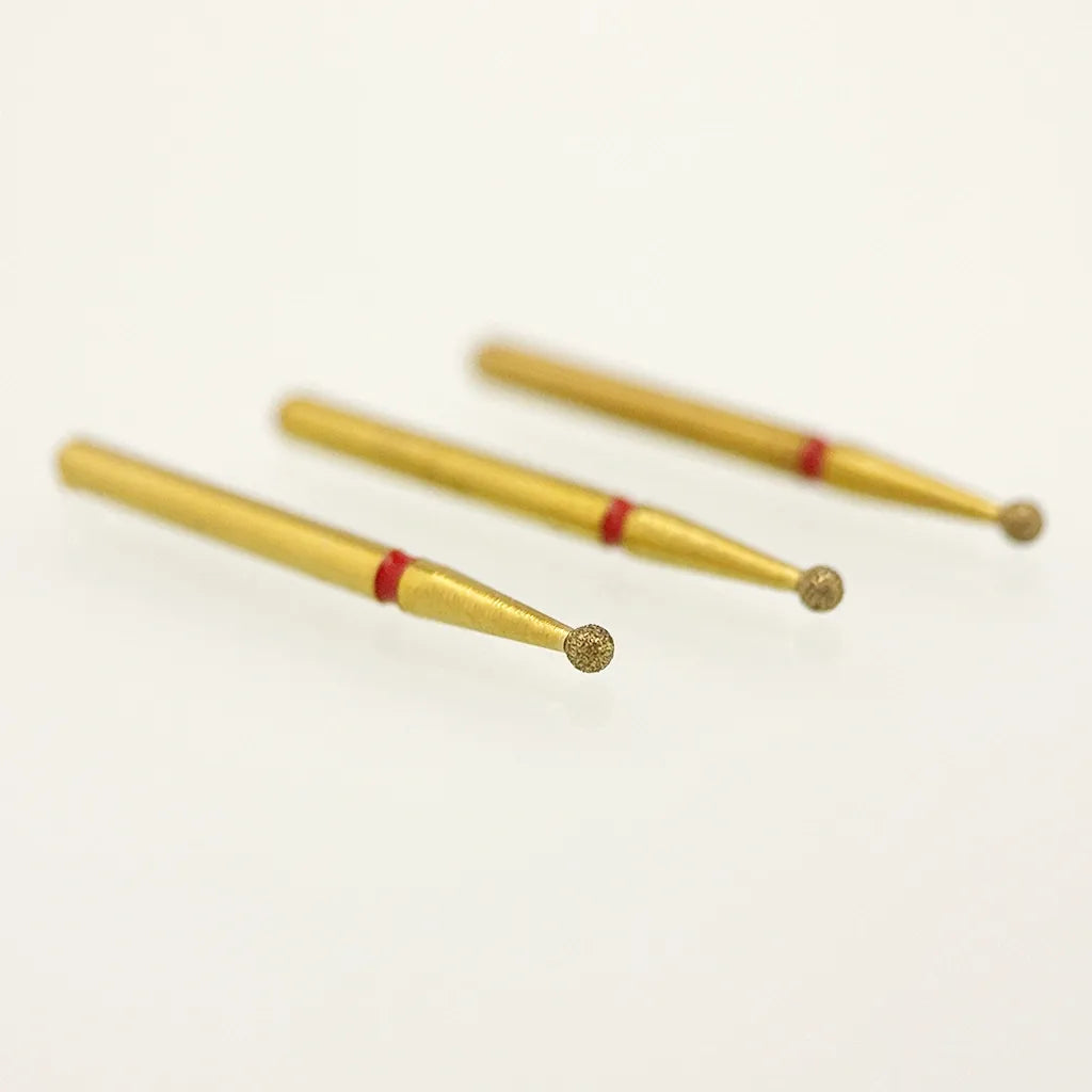 Three gold-colored nail drill bits with red bands on a white background