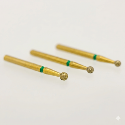 Three gold-colored dental burrs with green bands on a white background
